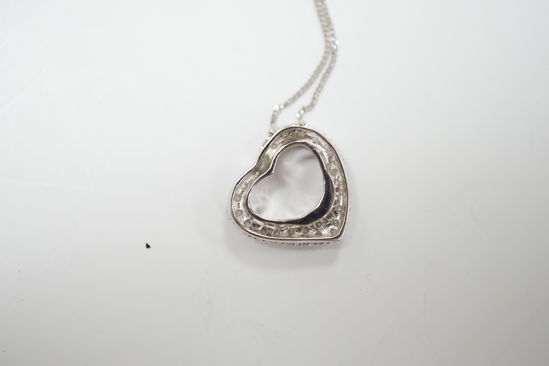 A modern 375 white metal and diamond chip set heart shaped pendant on chain, overall 42cm, gross weight 2.4 grams.